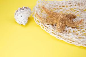 Starfish, shells with bag string bag on yellow background. Concept of summertime, vacation, travel. Copy space photo