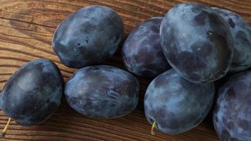 Tasty and ripe plums on brown wooden table photo