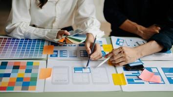 UX developer and ui designer brainstorming about mobile app interface wireframe design with customer breif and color code at office. photo