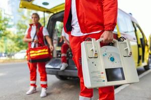 Hand of the doctor with defibrillator. Teams of the Emergency medical service are responding to an traffic accident.