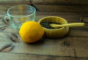 Glass mug with dried green tea and lemon. photo