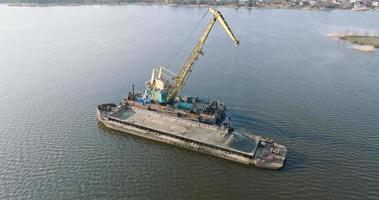 antenne visie Aan kraan uittreksels mineralen van bodem op reusachtig aak in midden- van meer of zee video