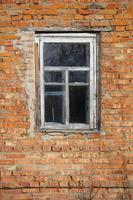 verticalmente ladrillo pared con un ventana en un antiguo rústico marco. foto