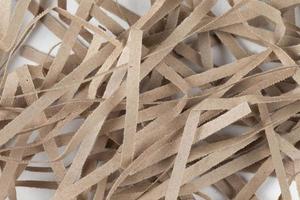 Lots of thin strips of beige paper. Decorative pieces of paper for gifts on a white background photo