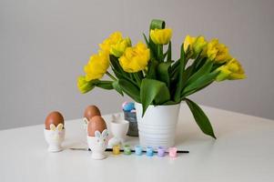 Easter banner with cute bunny shaped egg holders in pastel colors near tulips. Paint eggs. photo