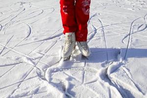 Legs of skater on winter ice rink in outdoors photo