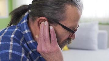 Close-up shot of old man with sore ears at home. Disease. Old man with earache is suffering and complaining about health problem. video