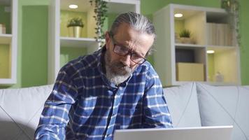 hoofdpijn. Mens op zoek Bij laptop een veel en werken moeilijk heeft een hoofdpijn. de oud Mens gebruik makend van een laptop Bij huis begint naar hebben een hoofdpijn en massages zijn hoofd. video