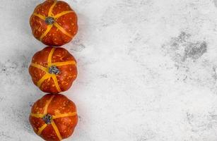 Thanksgiving or harvest copyspace banner with 3 mini pumpkins in a raw. Autumn holidays background. photo