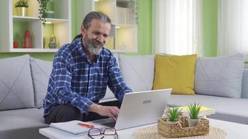 Mature man looking at laptop sitting at home feeling frustrated. Mature man seeing bad mail or news is disappointed, upset and not feeling well.
