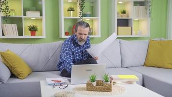 Middle-aged businessman working remotely at home thinking on project, executing ideas. Middle aged man working from home making plans, working on projects and documents in living room. video