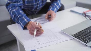 mature ingénieur homme travail sur projet de maison. milieu vieilli ingénieur homme séance sur canapé à Accueil dessin projet en utilisant portable. video