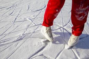 Legs of skater on winter ice rink in outdoors photo
