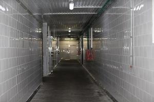 An empty corridor of a factory or workshop is faced with tiles and concrete floor. photo