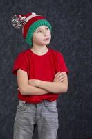 Funny little boy in a knitted Christmas hat on a gray background. photo