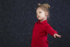 Beautiful little girl in a red dress stretches out her hand. photo