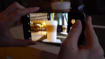 niña hace un foto de café en un teléfono inteligente en un café cerca arriba video