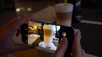 niña hace un foto de café en un teléfono inteligente en un café cerca arriba video