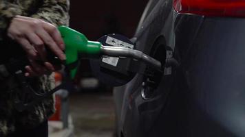 Woman inserts a fuel gun in a gas tank to refuel a car video