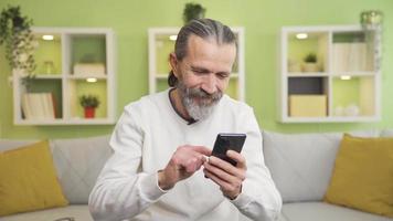 el antiguo hombre mirando a el teléfono a hogar obtiene emocional y triste. el antiguo hombre es emocional y entristecido por qué él ve en el pantalla de su teléfono inteligente a hogar.