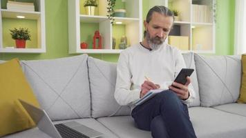 homem procurando e analisando estoque mercado dados. a comerciante parece às a gráficos em dele computador portátil e telefone e análises eles. video