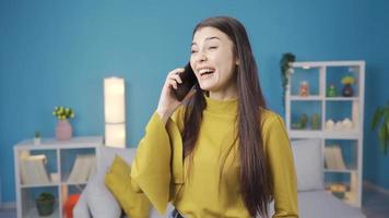 Happy young woman talking on the phone, smiling, white teeth and big passengers. Beautiful attractive young woman gets happy smiling while talking on the phone at home. White and shiny teeth. video