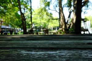 Old Wood Table with Nature Bokeh in Public Garden Background, Suitable for Background, Backdrop, and Mock up. photo