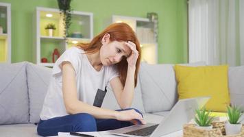 joven mujer trabajando en ordenador portátil considerado, en problema, confundido. joven mujer mirando a ordenador portátil infeliz a hogar preocupadamente trabajando en computadora portátil, en problema. video