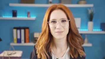 Young business woman taking off her glasses in office smiling at camera. Office worker young woman smiling, feeling positive and peaceful. video