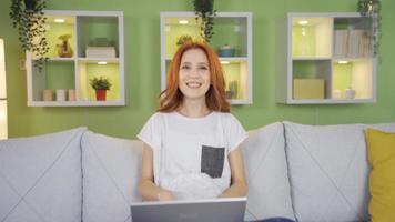 Rejoicing young woman. Young woman looking at laptop rejoices.  Young woman sitting on the sofa at home is delighted with what she sees on the laptop. Action camera. video