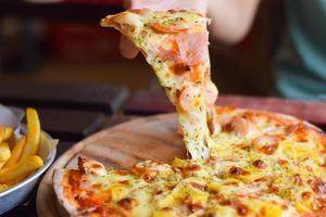 pizza de queso hawaiano sobre mesa de madera. concepto de comida casera foto