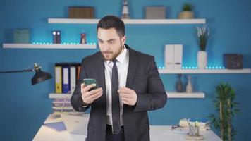 homem de negocios recebe Boa notícia ou mensagens em a telefone. uma homem de negocios usando uma Smartphone recebe Boa notícia e é feliz. video