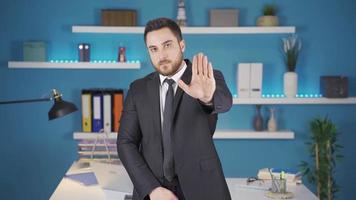 Businessman making stop sign at camera. Serious businessman looking at camera in office making stop sign. video