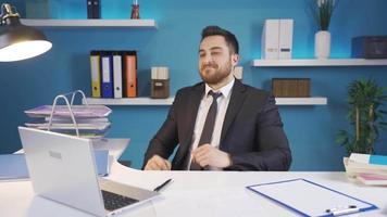 Businessman rejoices at what he sees on laptop and looks at camera with a smile. The businessman in the office is happy and smiling at the view he sees on his computer. video