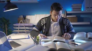 Jeune homme en train de lire une livre dans le bibliothèque pièce apprend Nouveau information. Jeune homme qui aime à recherche et lis livres est dans le sien étude. video
