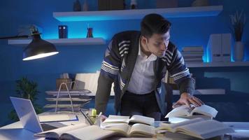 Concentrated senior male researcher working in study room late at night. The young researcher reading a book wants to reveal the truth about the subject he is interested in. video