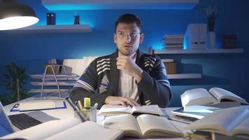 University student reading a book. The student is reading a book at home. He has laptop and books on his desk. video