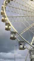 Ferris Rad im das Amüsement Park auf Hintergrund von grau bedeckt Himmel mit Wolken. niedrig Winkel Aussicht von ein groß Ferris Rad. video