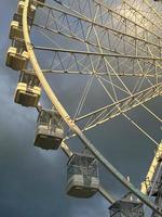 ferris rueda en el diversión parque en antecedentes de gris nublado cielo con nubes bajo ángulo ver de un grande ferris rueda. foto