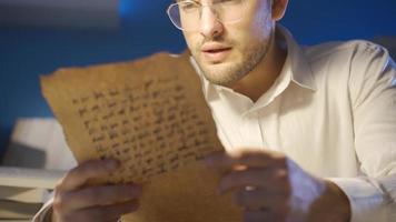 examinando el histórico letra escrito en el medieval alfabeto, el historiador lee eso en el luz, seriamente y enfocado video