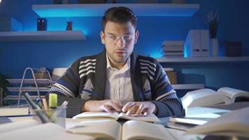 joven hombre leyendo un libro en su estudiar. talentoso joven hombre con lentes leyendo libro para trabajo en clase y examen preparación. video