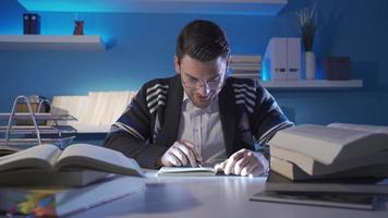 Happy and pleasant young man reading a book, doing research, collecting information and data. The young researcher reading the book finds the information he is looking for and smiles happily. video