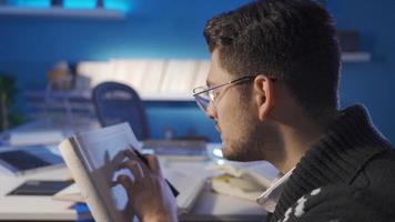 Close-up of young man reading a book, doing research, doing homework. Close-up of young man in glasses reading a book, doing research, looking for information. video