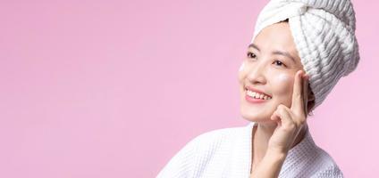 Young asian woman applying facial skincare face cream, cosmetic moisturiser on healthy natural skin make up face. Portrait glowing smile girl person model with care beauty product, spa, cosmetology. photo
