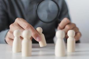 Hand Holding A Magnifying Glass Focusing On Wooden Figure .job search, human resources, hiring Concept photo