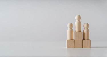 wooden figures peg doll standing on the podium of wooden cube blocks with copy space. ranking and strategy concept. photo