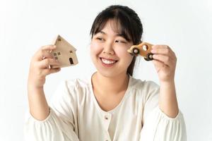 compradora asiática que elige entre comprar una casa nueva o un automóvil. Planeando comprar casa y auto. foto