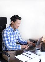 un hombre en un comprobado camisa trabajando desde hogar a un escritorio foto