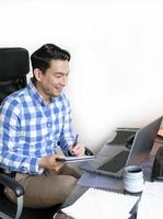 A man in a checked shirt working from home at a desk photo