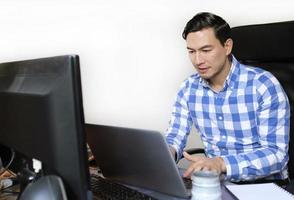 A man in a checked shirt working from home at a desk photo